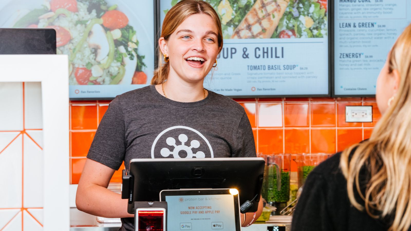 Protein Bar & Kitchen team member greeting a guest at the register