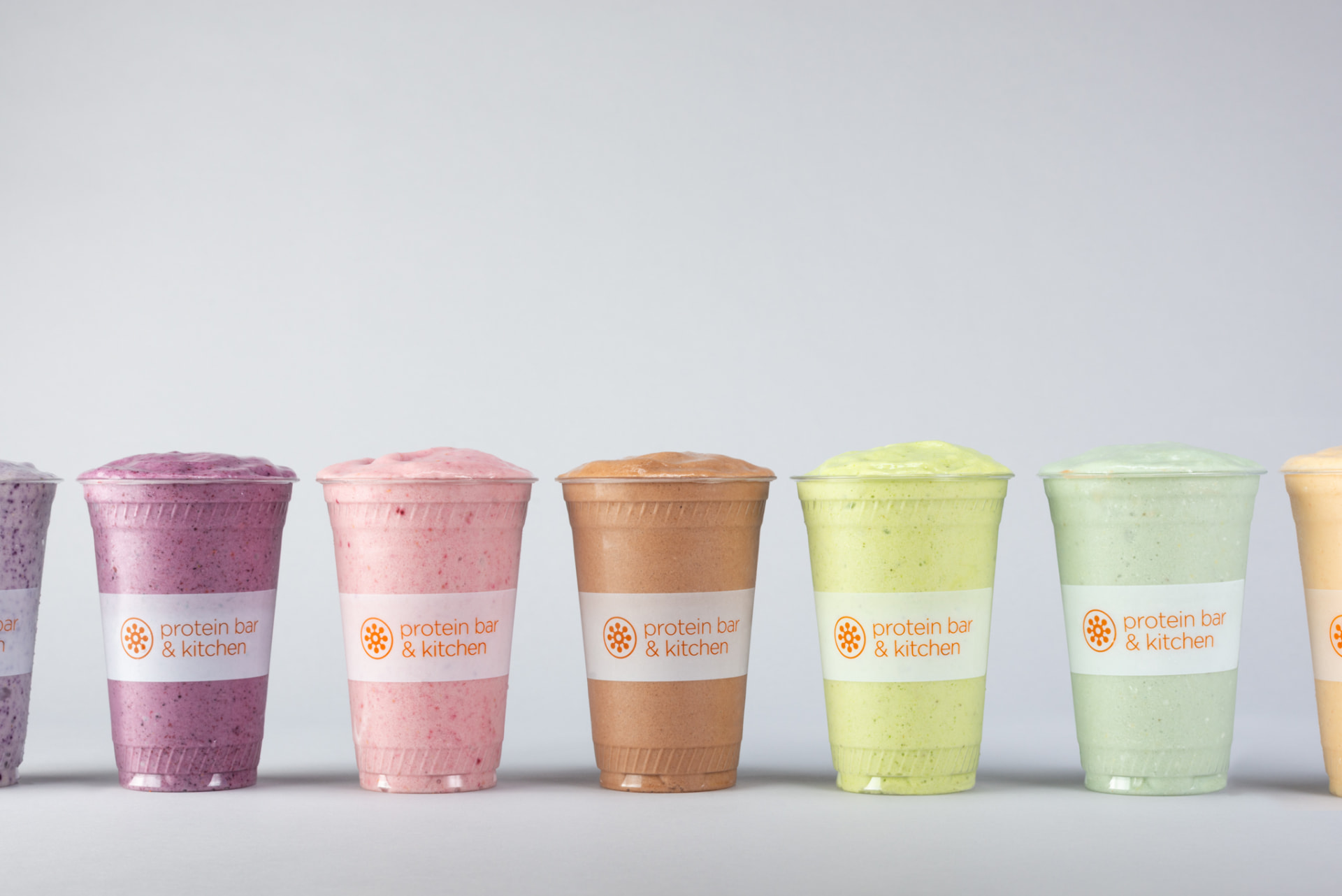 A lineup of Protein Bar & Kitchen blended shakes and smoothies in branded cups