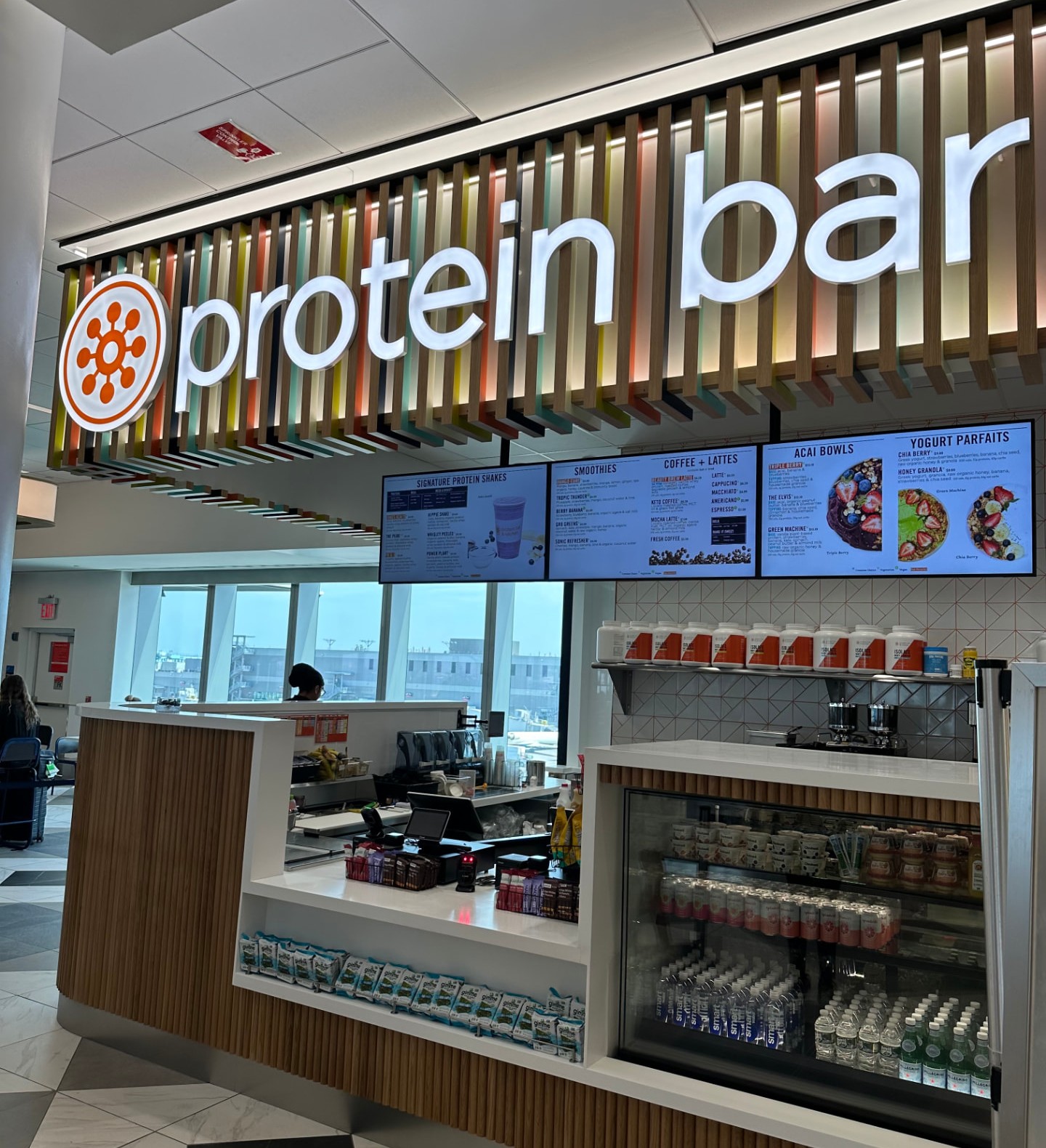 Protein Bar & Kitchen counter with illuminated signage and digital menu boards at LaGuardia Airport