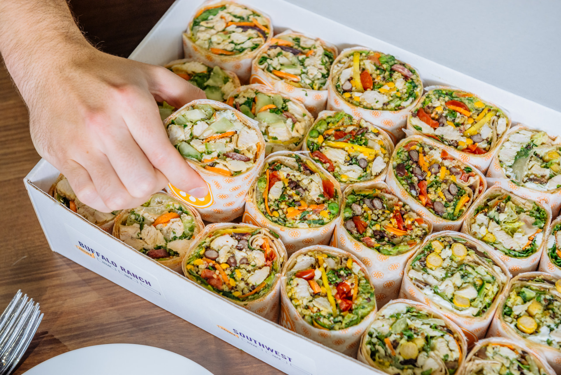 A Protein Bar & Kitchen catering box filled with assorted wraps